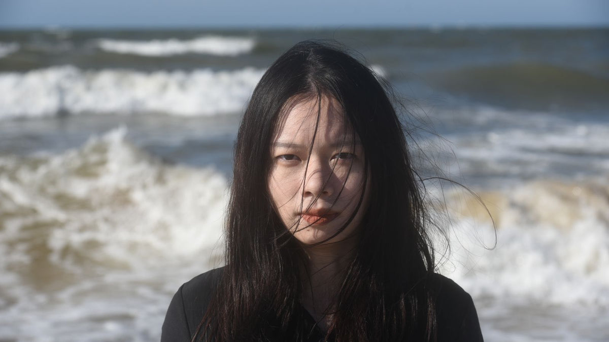 Woman with hair blowing by the ocean shore, asking is salt water good for hair