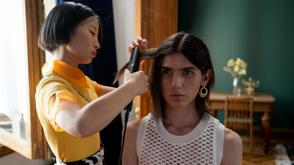 Hairdresser using a flat iron to seal a keratin hair treatment in a salon