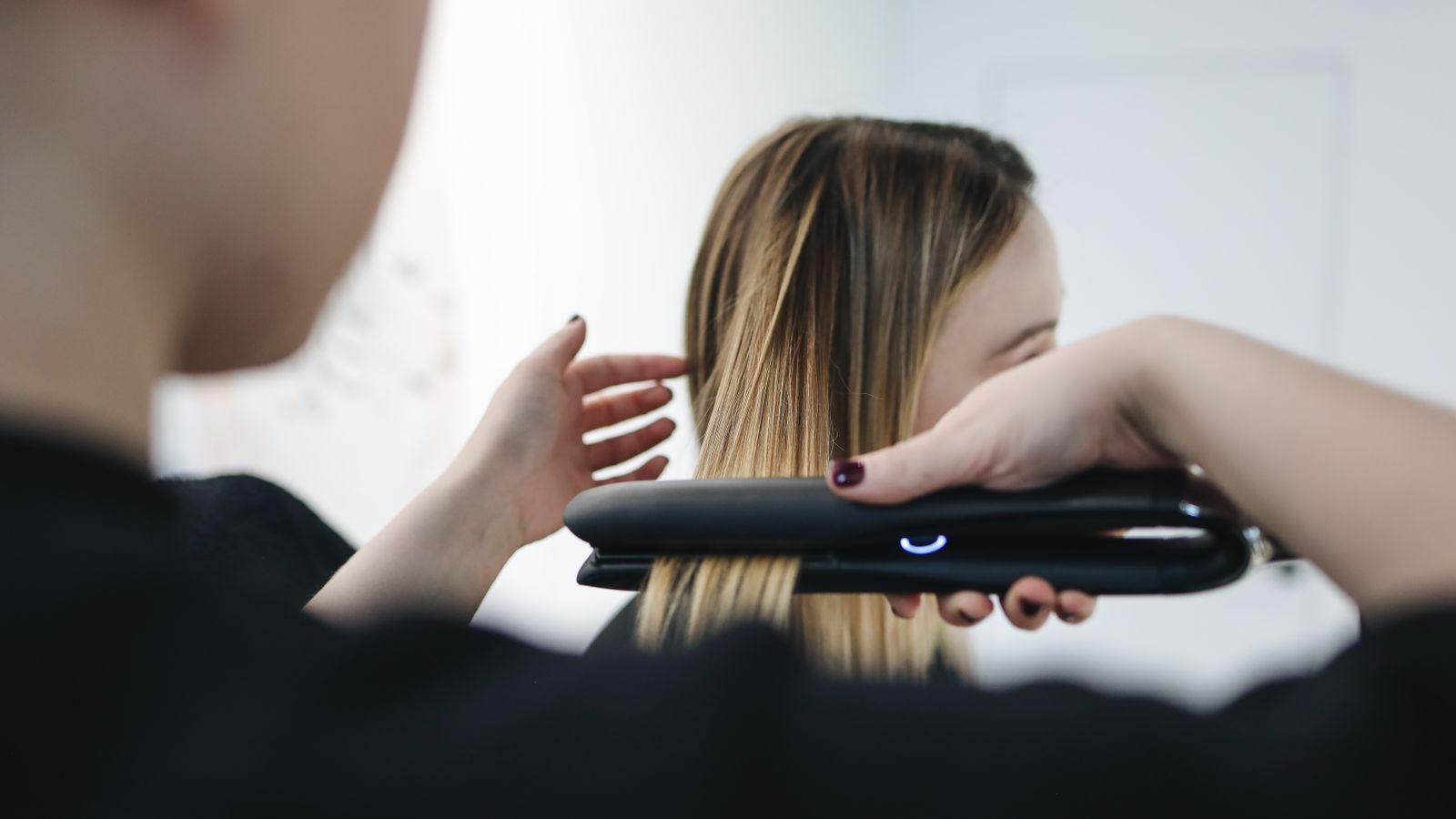 Stylist using a straightening iron during a keratin treatment on thin hair