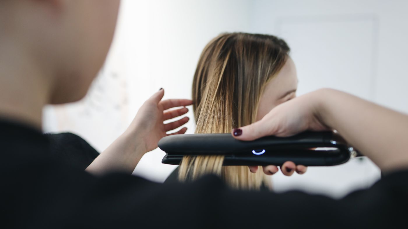 Stylist running a straightening iron through smooth hair after a keratin treatment