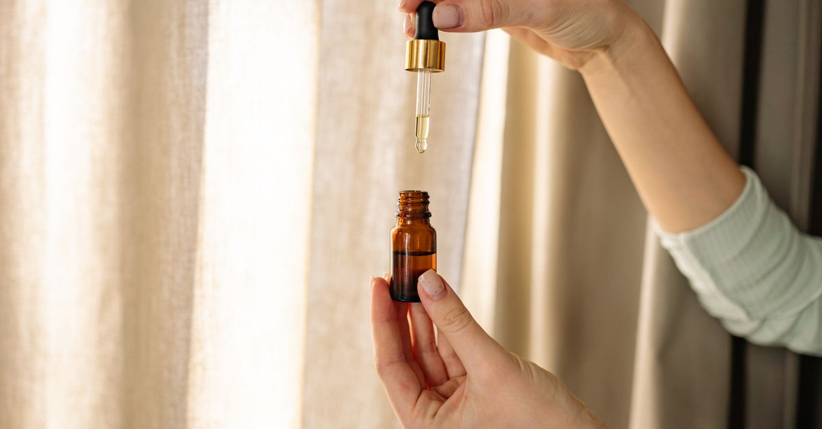 Hands holding a dropper and amber bottle, the format used for liquid biotin for hair