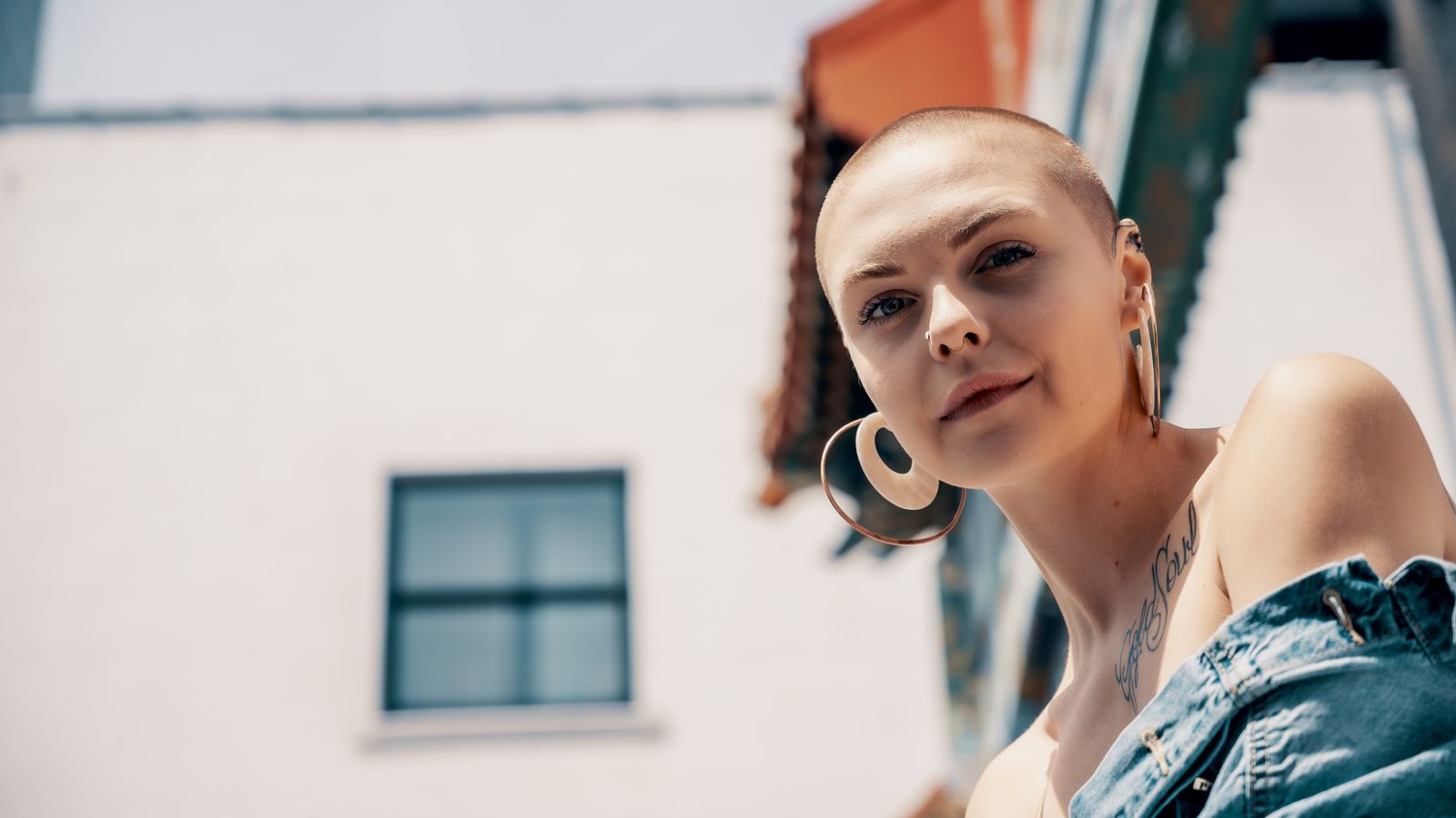 Woman with alopecia standing confidently in a denim jacket, living with alopecia areata