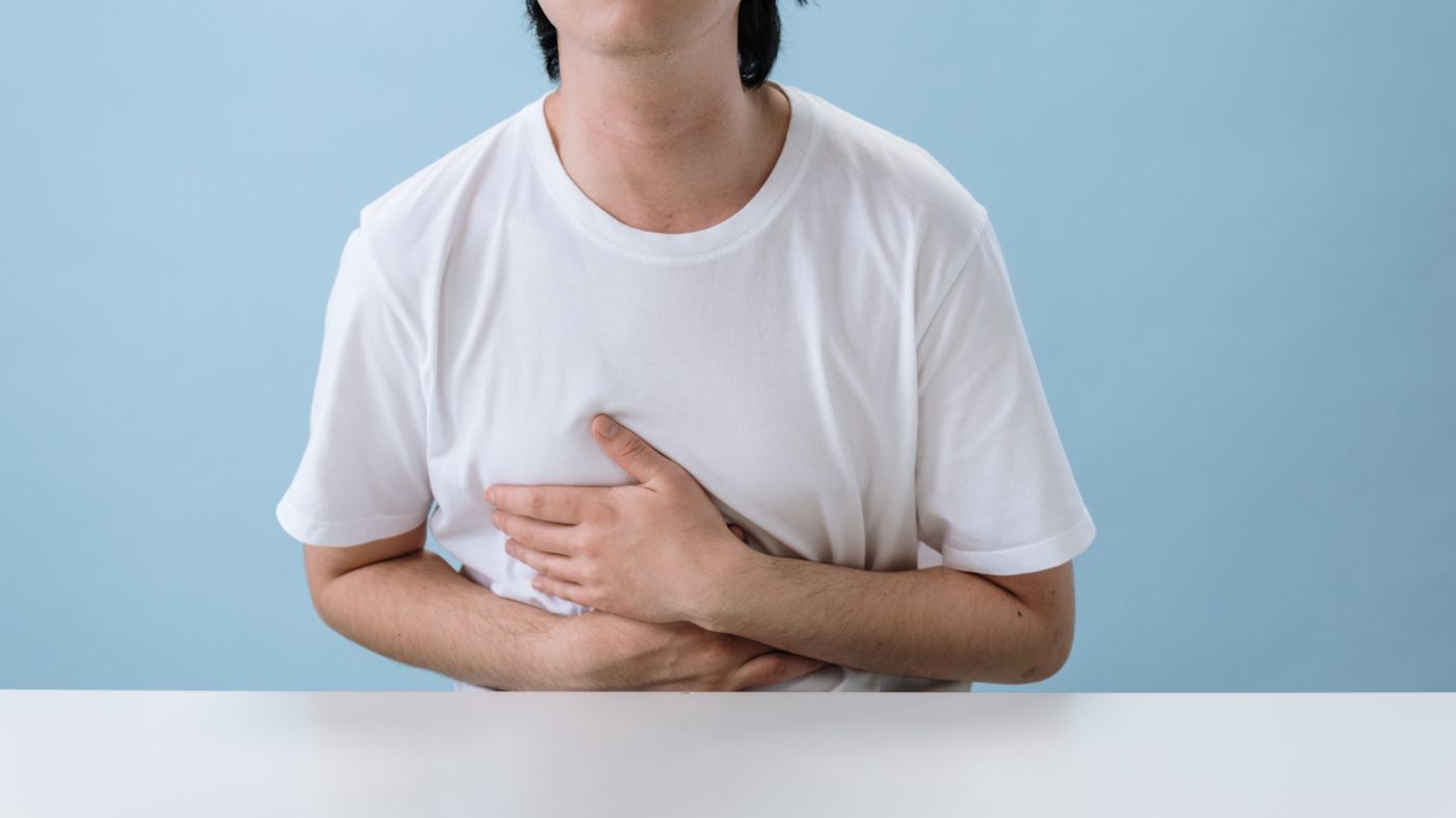Man holding his stomach with reflux discomfort, the reason many people start long term PPI treatment