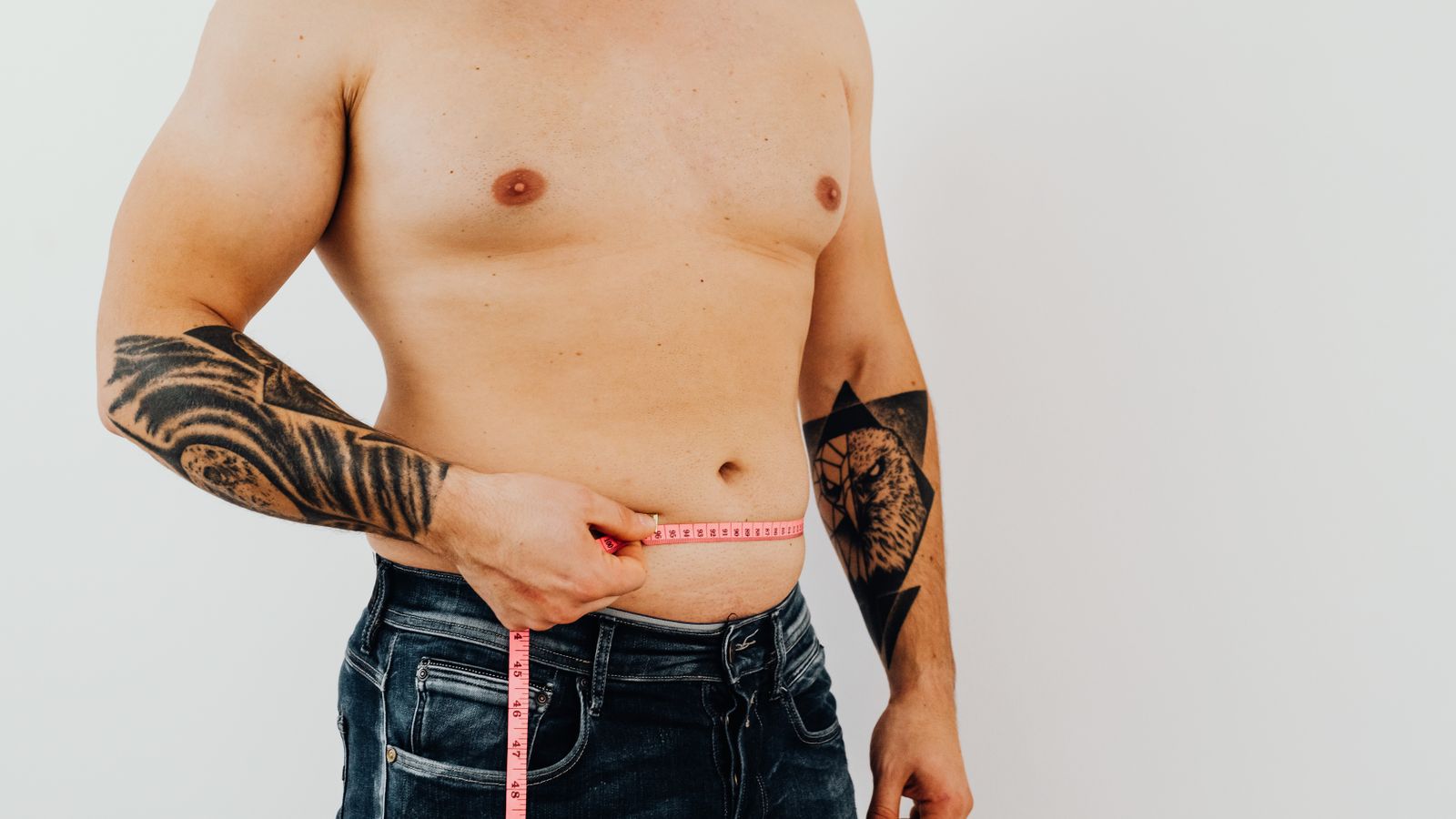 Man measuring his waist, checking abdominal fat linked to low testosterone belly