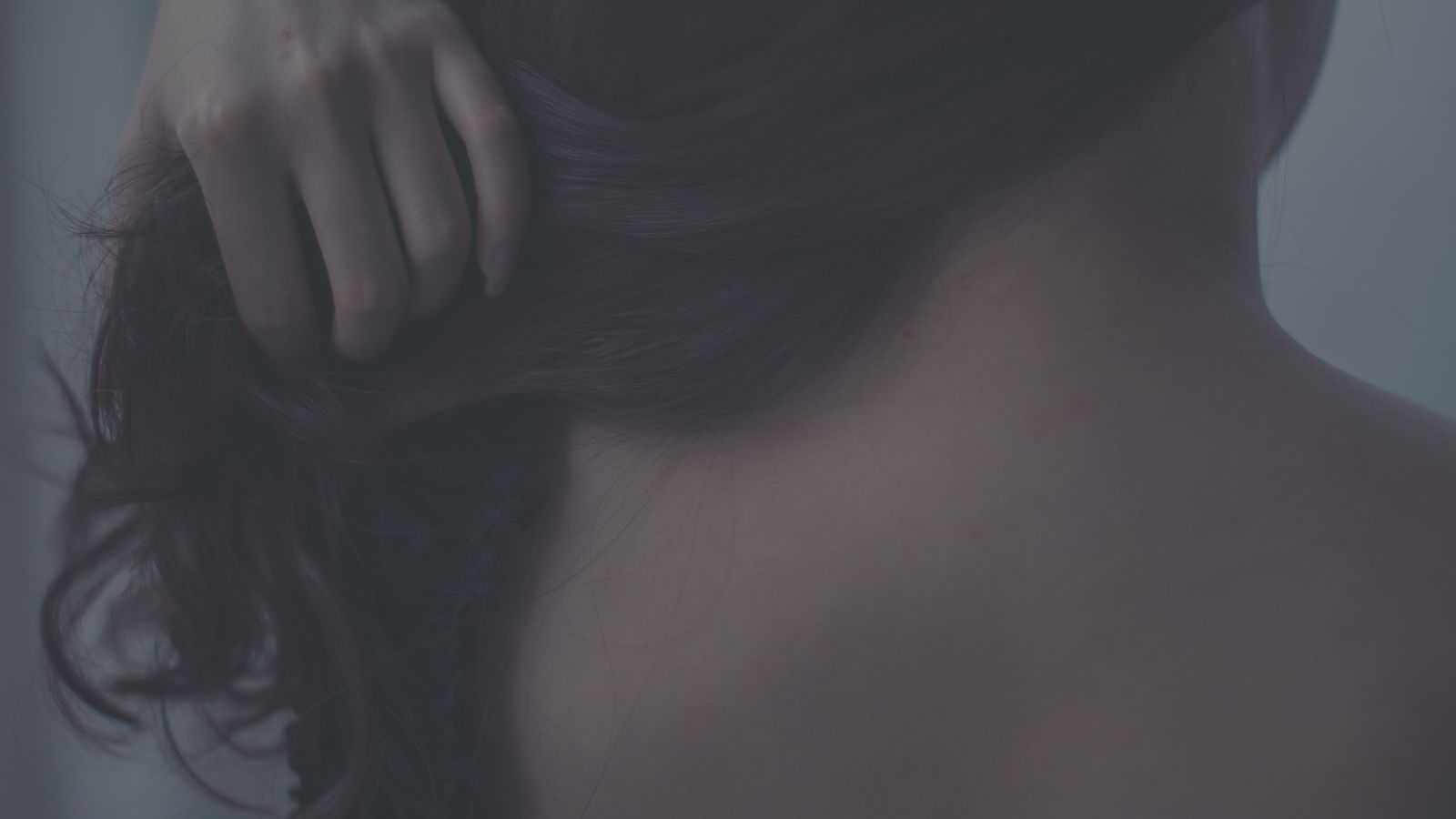 Woman gently touching her hair, coping with lupus hair texture changes