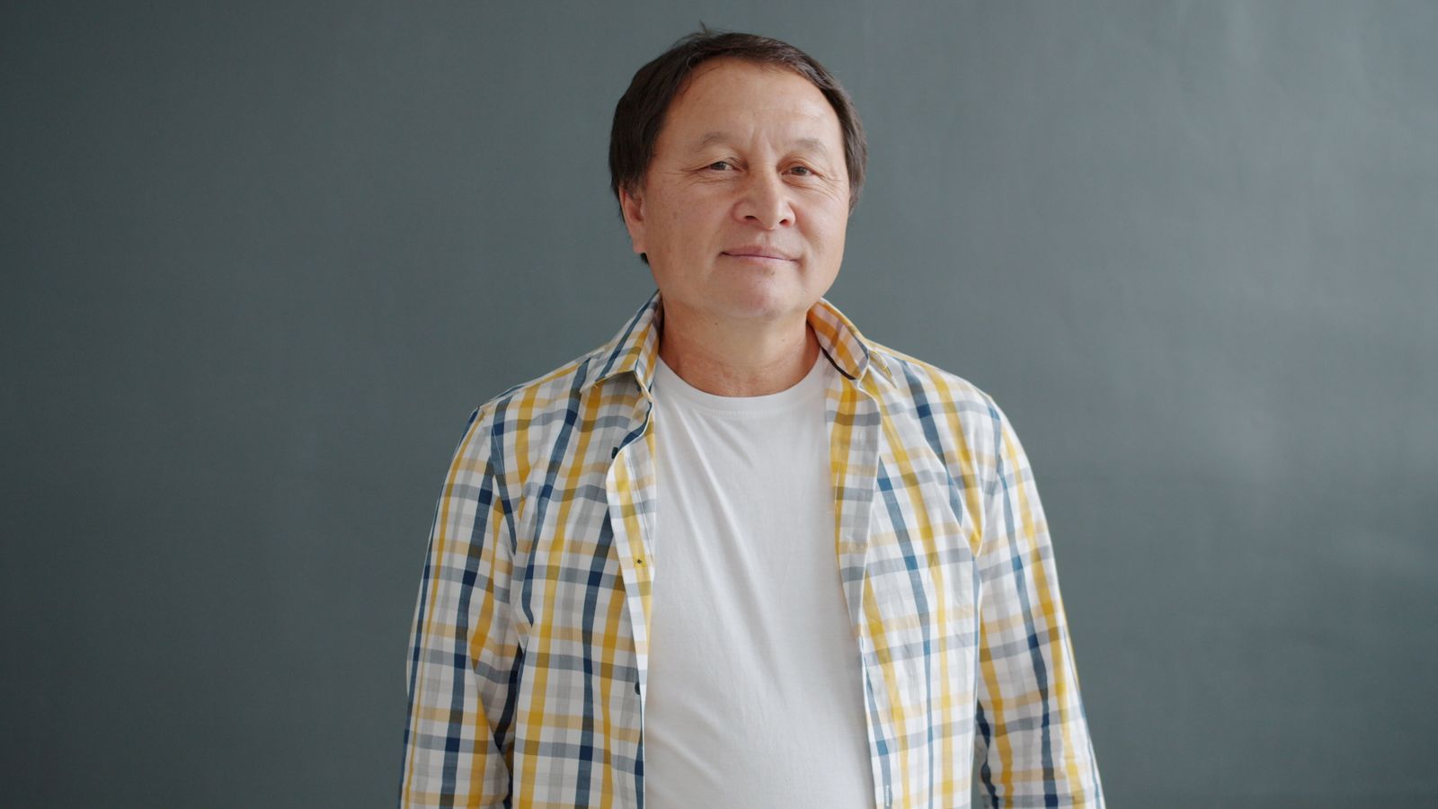 Confident mature man with a mature hairline smiling in a plaid shirt