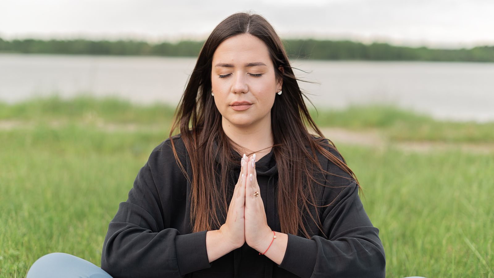Woman meditating calmly outdoors, meditation for hair growth and stress relief