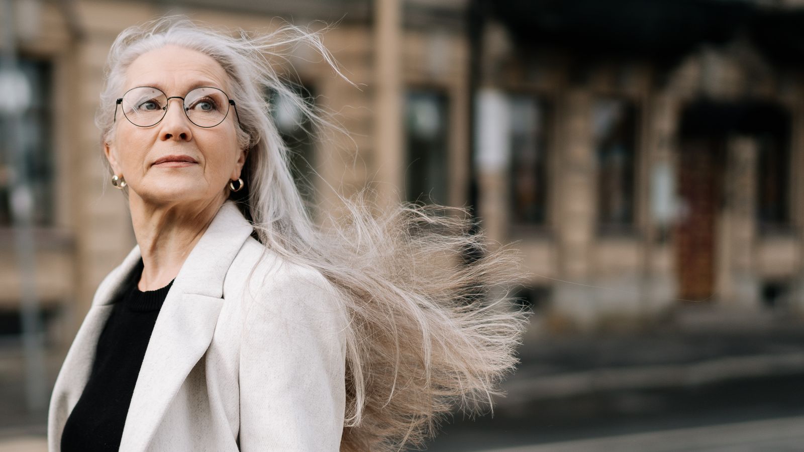 Woman with silver hair walking outdoors, staying confident through menopause hair loss thinning