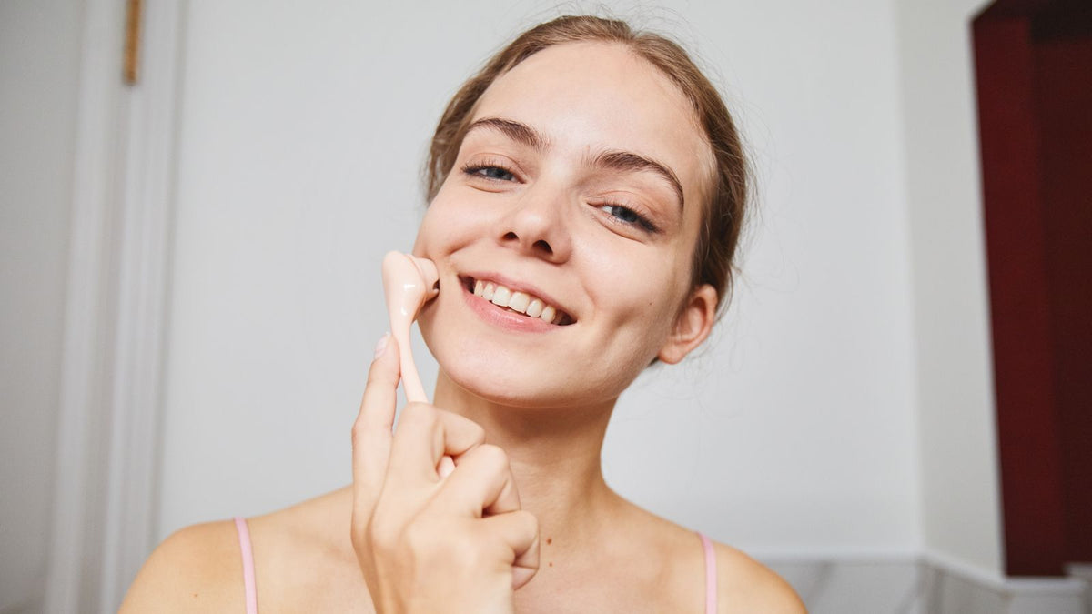 Woman using a facial roller in her skincare routine, the tool type people ask about for microneedling for hair loss at home