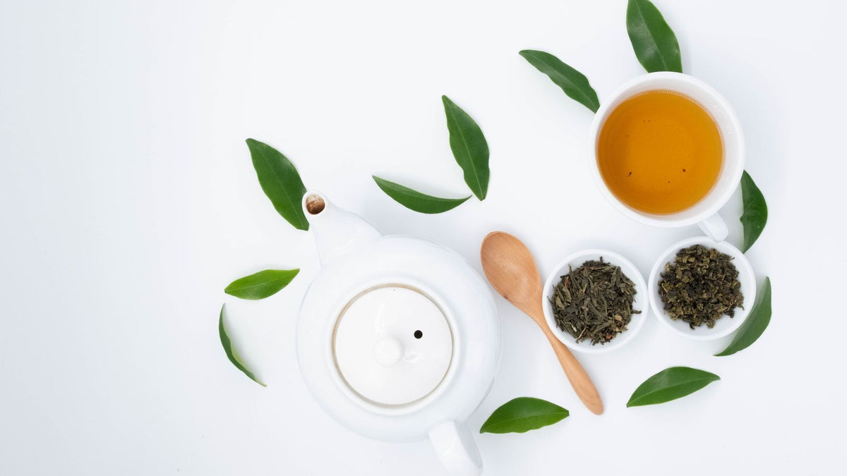A cup of green herbal tea beside dried leaves, illustrating nettle tea benefits for hormones