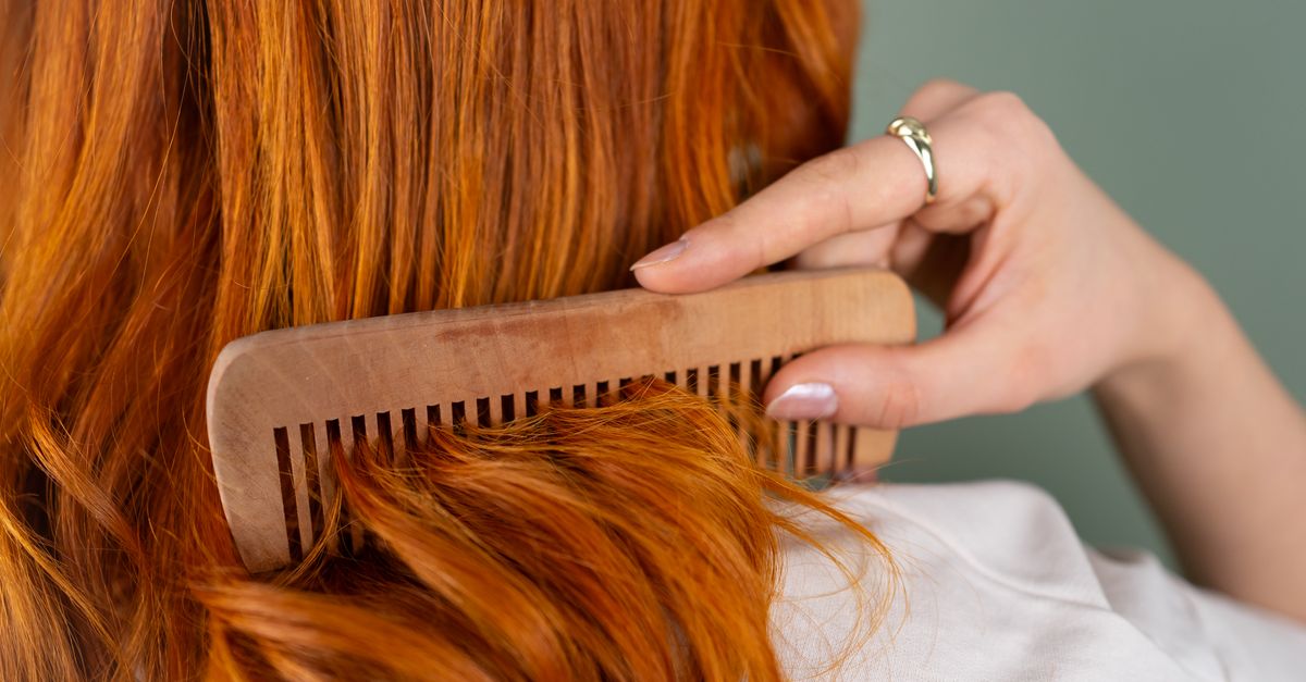 Woman combing long hair with a wooden comb, the everyday routine niacinamide for hair fits into