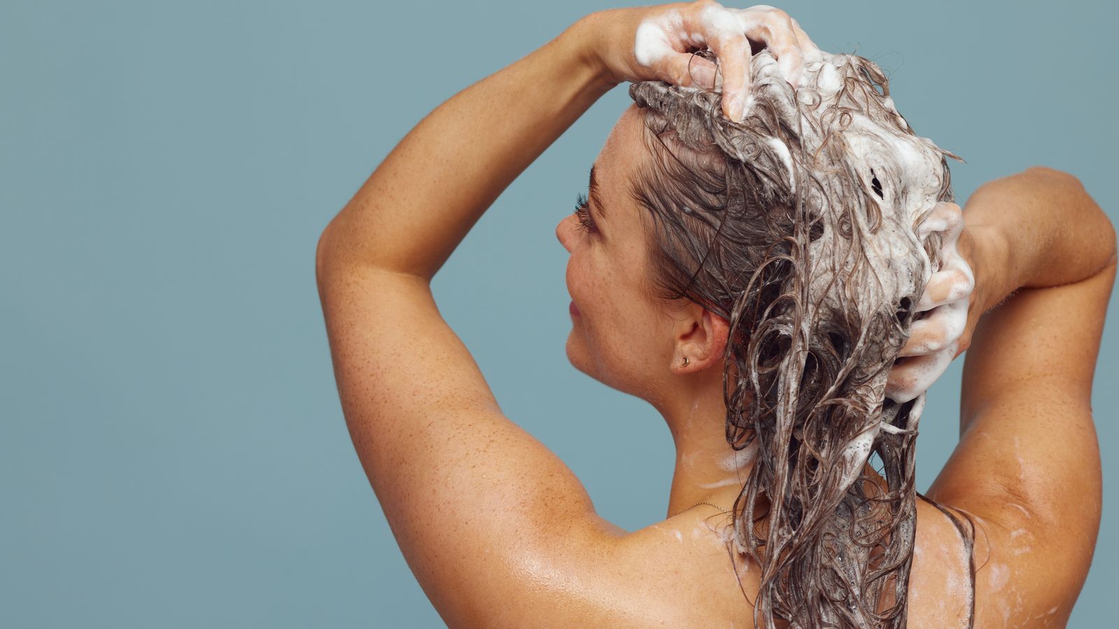 Woman lathering shampoo at the roots, the right approach for an oily scalp and dry ends