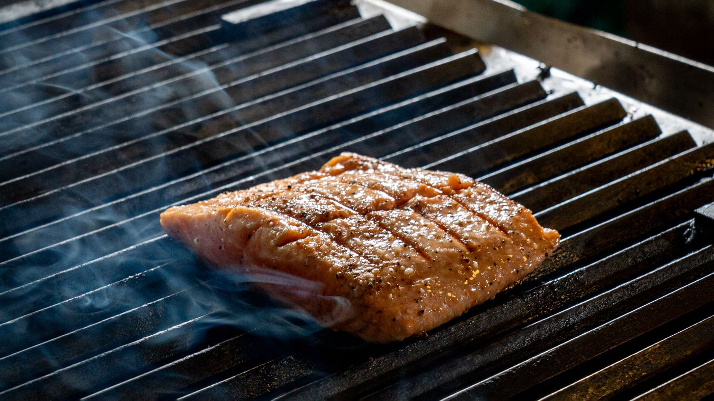 Salmon fillet cooking on a grill, one of the best food sources of omega 3 for brain health