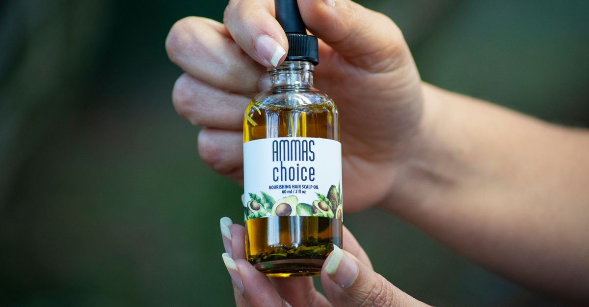 Hands holding a bottle of batana hair and scalp oil