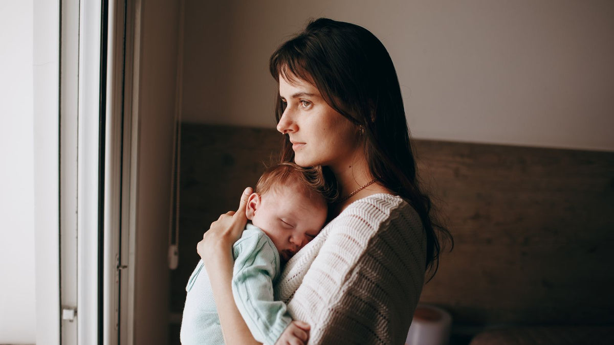 New mother holding her baby while going through postpartum hair loss