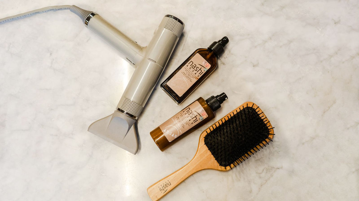 Flat lay of hairdryer, brush and styling products, the core products for fine thin hair
