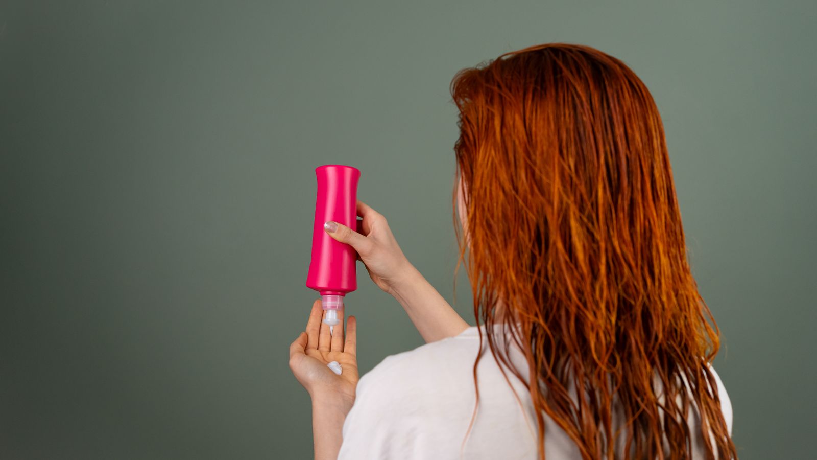 Woman with wet red hair applying conditioner as part of the steady routine people hope will remove DHT from scalp skin