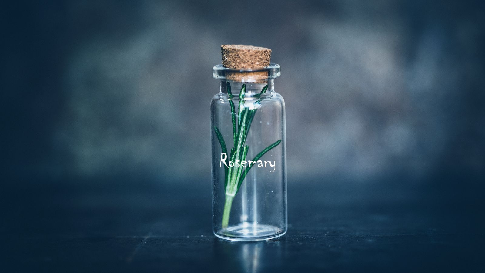 Fresh rosemary sprig in a glass oil bottle showing rosemary oil benefits for hair