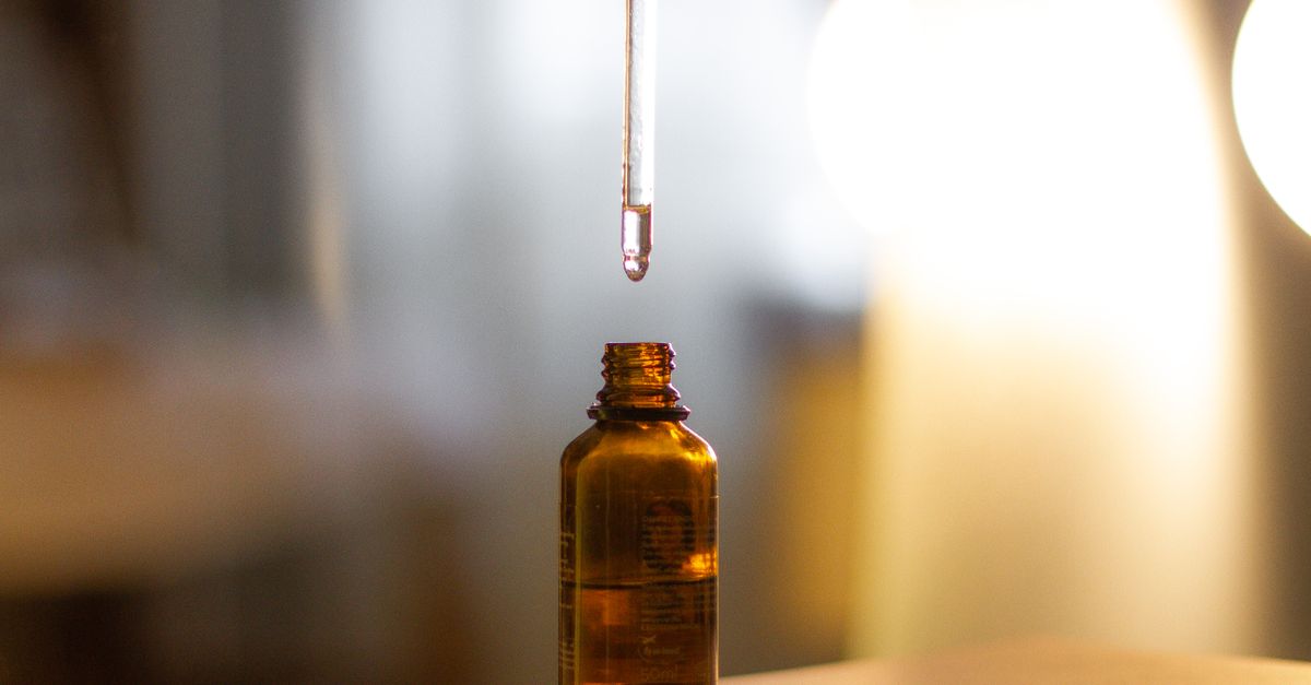 Glass dropper above an amber bottle, diluting rosemary oil for thinning hair