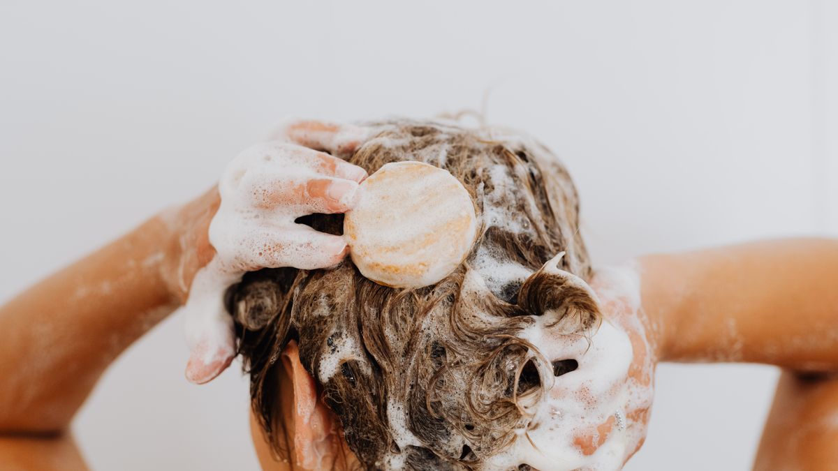Close up of hands washing hair with foam, the gentle cleansing routine that helps calm scalp folliculitis