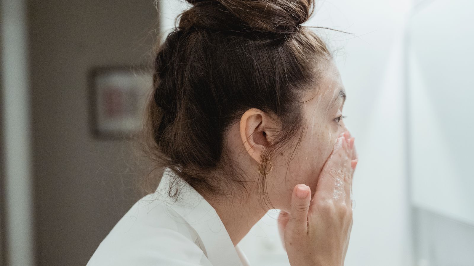 Young woman washing her face, the first step in a skin care routine for combination skin