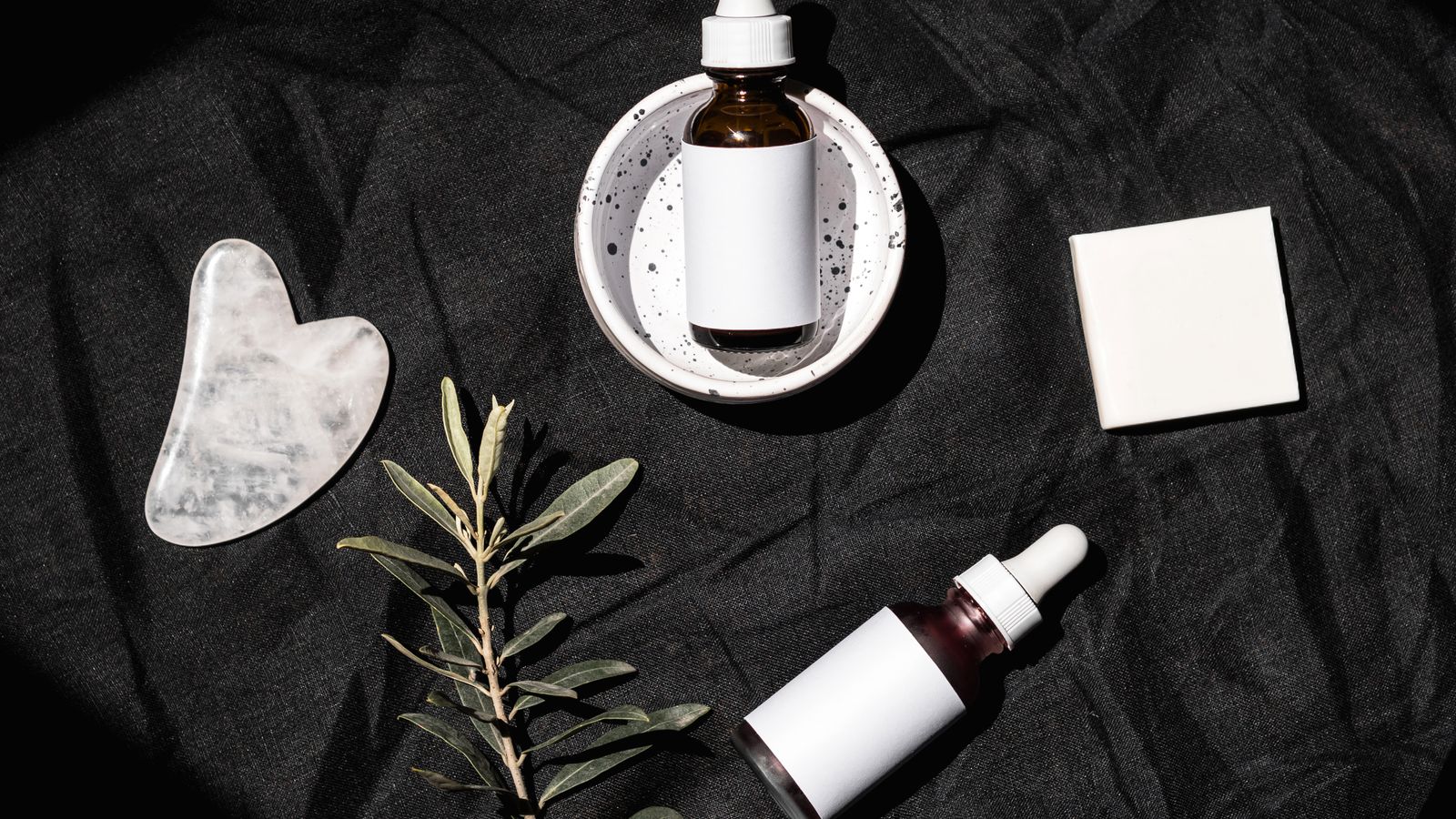Flat lay of skincare serum bottles and a gua sha tool, illustrating skincare routine order