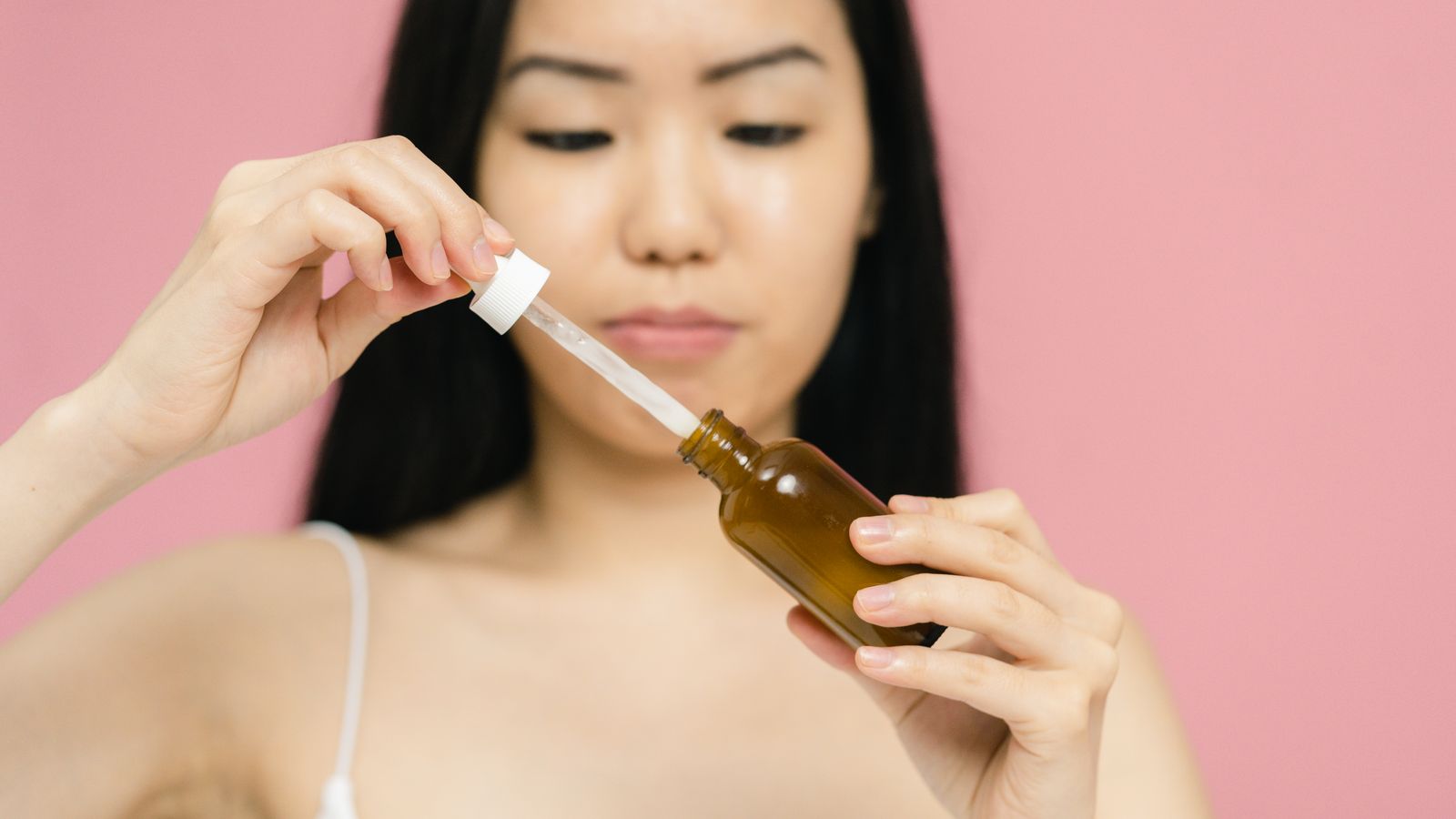 Woman holding a serum dropper bottle, illustrating snail mucin benefits for skin