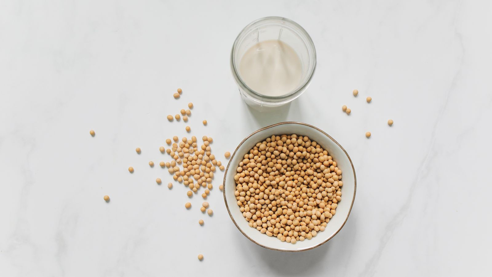 Soybeans in a bowl beside a glass of soy milk, the whole food source behind soy protein isolate