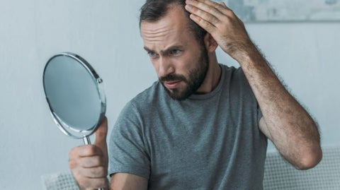 Man checking his hairline for signs of pattern hair loss