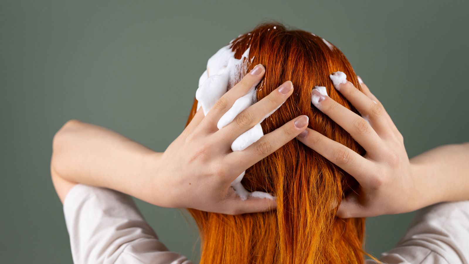 Back view of long red hair being washed, showing how a sulfate free shampoo cleans without stripping