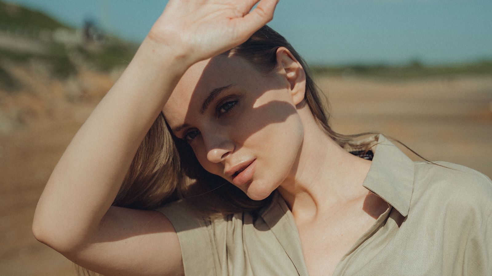 Woman shielding her eyes from bright sunlight, illustrating why sunscreen for oily skin still matters