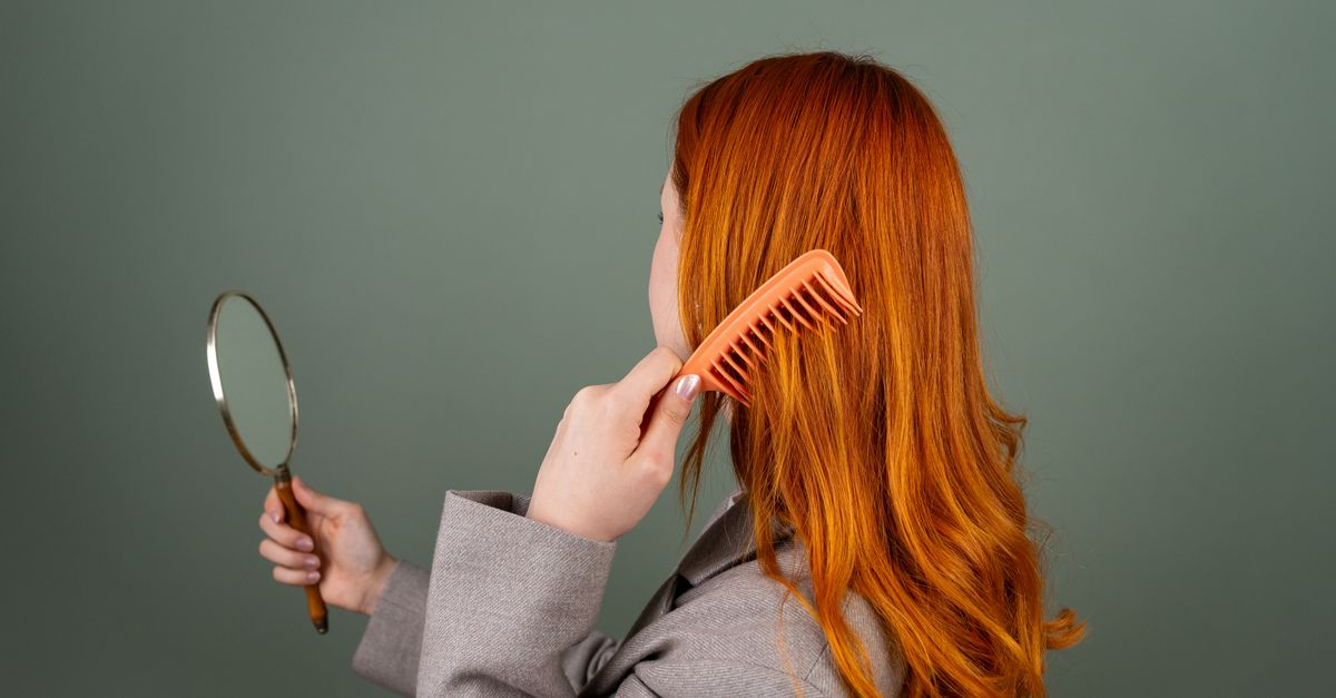 Woman combing her hair at a mirror, checking shedding during telogen effluvium