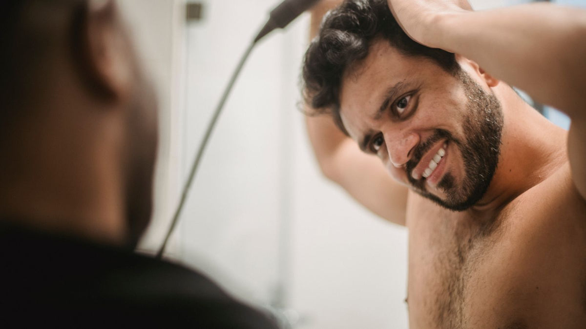 Man styling his hair at the bathroom mirror while wondering about testosterone and hair loss