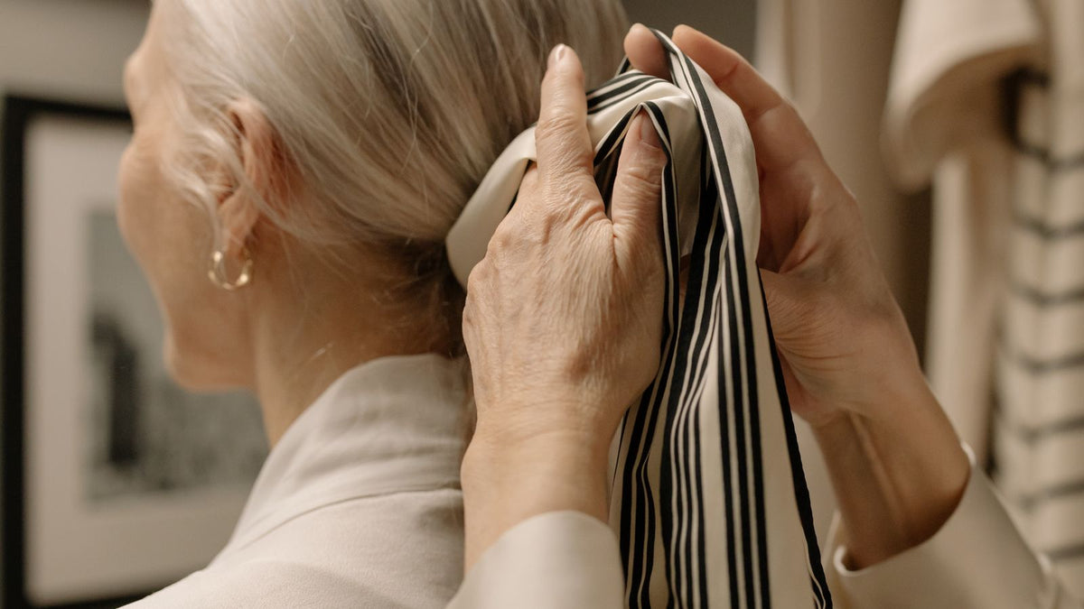 Woman in her fifties reviewing thinning hair after menopause in the mirror