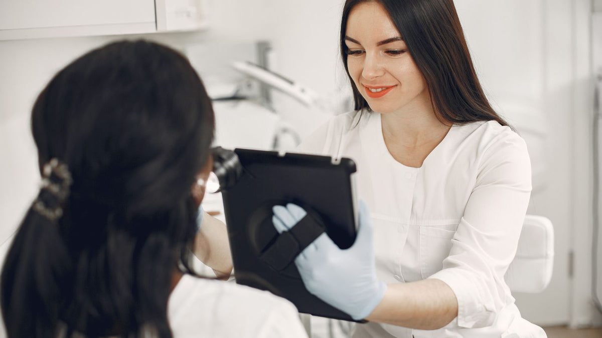 Specialist talking a client through notes on a tablet, much like a trichologist consultation