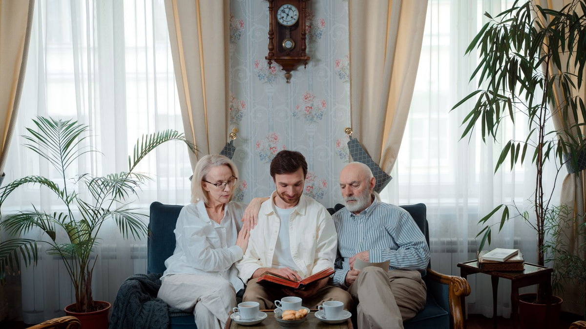Adult son looking through a family photo album with his parents, tracing the hair pattern a trichologist in Colchester will ask about