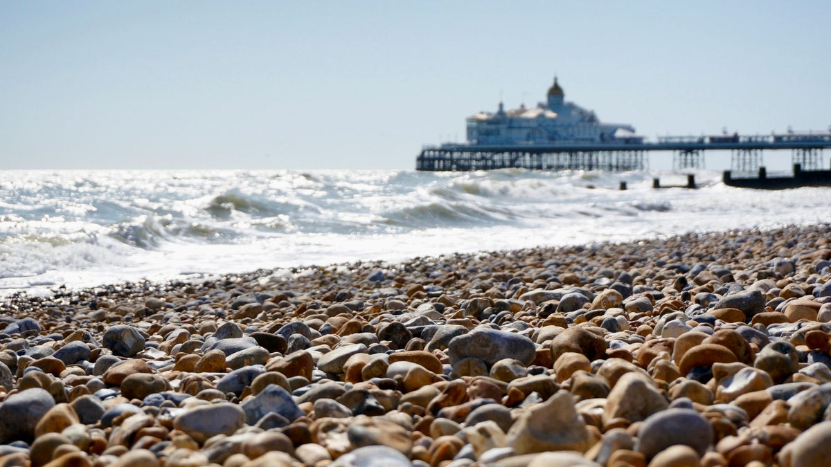 Eastbourne pebble beach and pier on a clear summer day, the setting for this trichologist in Eastbourne guide to protecting a thinning scalp from the sun