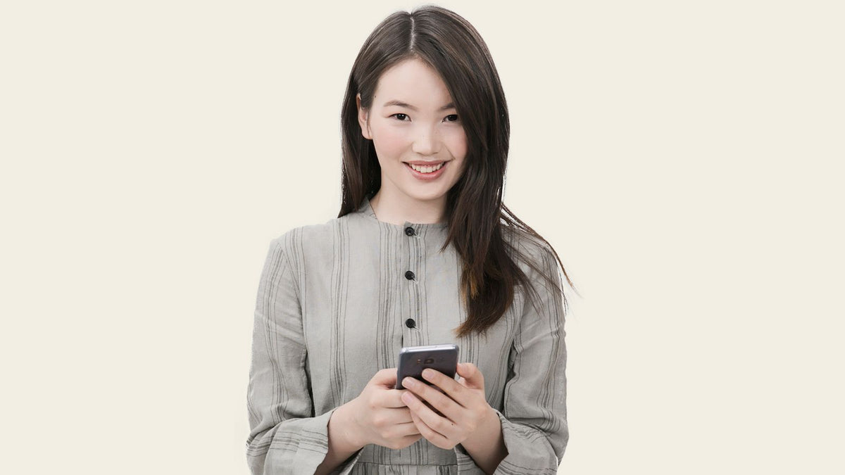 Woman with long hair checking viral hair growth hacks on her phone before deciding whether to see a trichologist in Folkestone