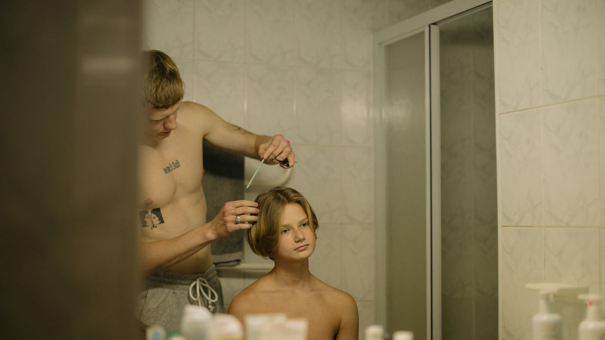 Trichologist Romford: a young man checking his hairline in the bathroom mirror