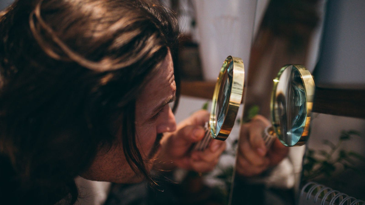 A person inspecting hair closely with a magnifying glass, the kind of look behind the notes in a trichologist Twickenham report