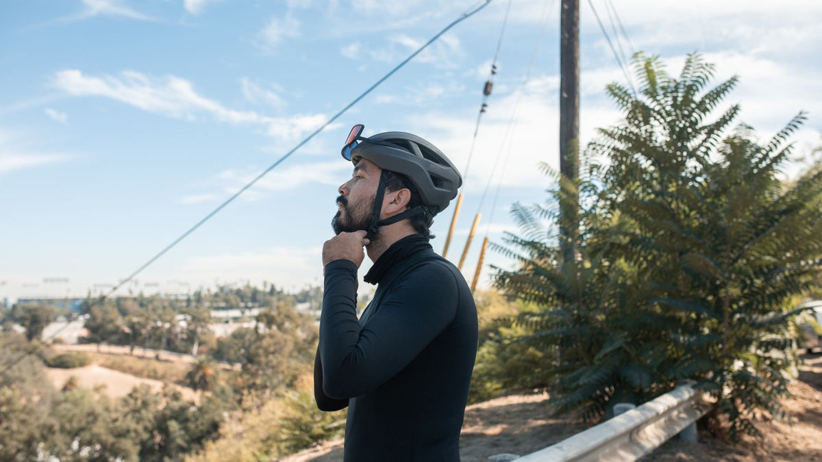 Cyclist adjusting his helmet before a ride, the kind of daily habit people ask trichologists Cambridge about when they worry about helmet hair loss