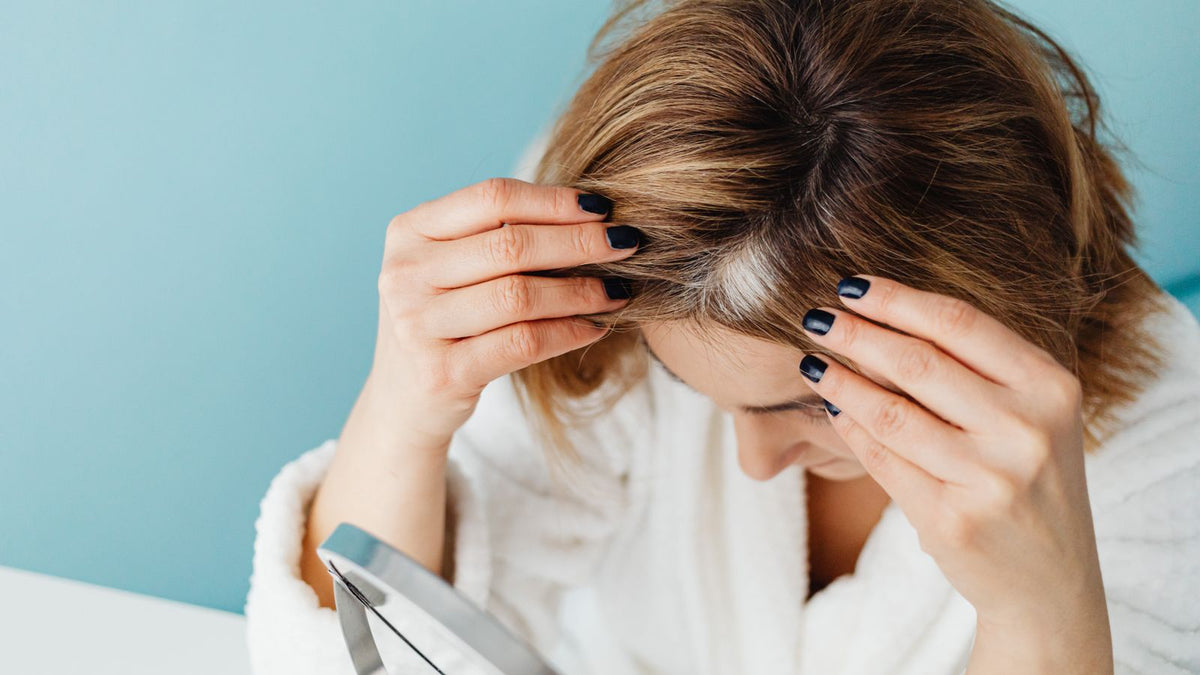 Woman checking her parting in a mirror before booking trichologists Greenwich
