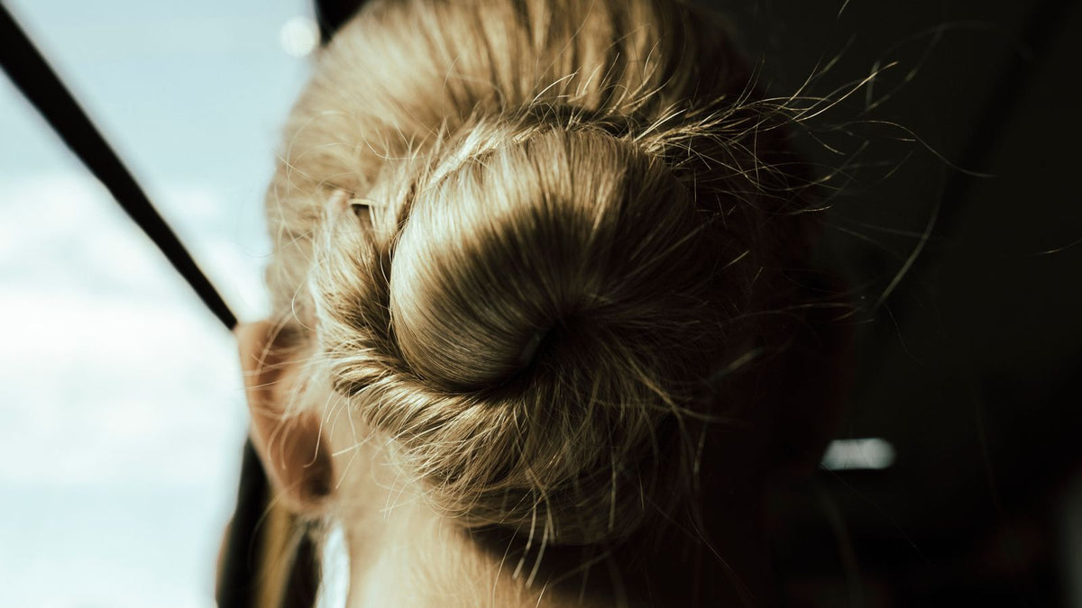Sunlit blonde hair bun resting at the nape of the neck, the friction spot this trichologists in Bebington guide covers