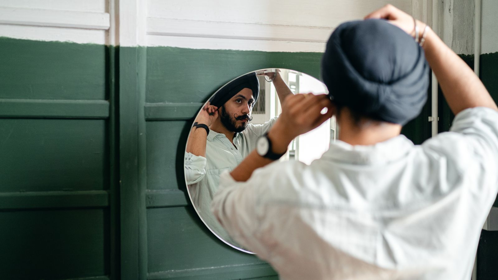 Man checking his hairline in a mirror before seeing a trichologist in Merthyr Tydfil