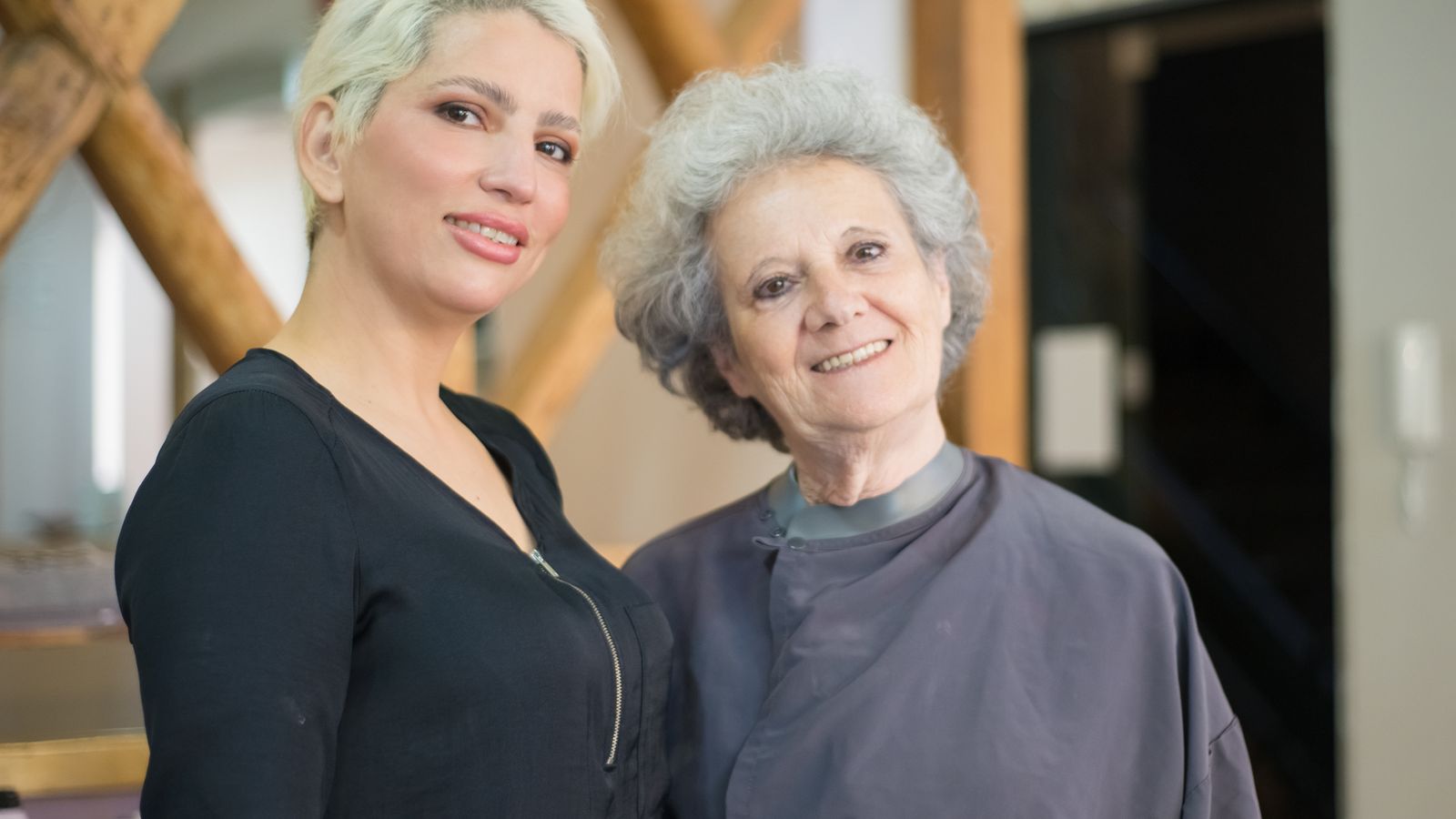 Smiling stylist with an older client in a salon, a guide to trichologists in Motherwell