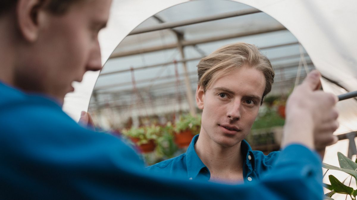 A young man checking his hair in a mirror before contacting trichologists Nottingham