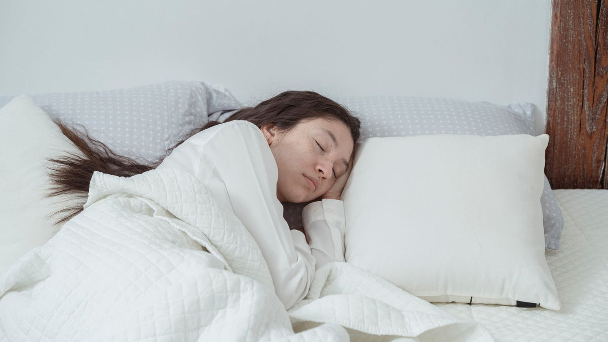 Woman with long dark wavy hair asleep on a white pillow, the overnight hair question behind many trichologists Slough searches