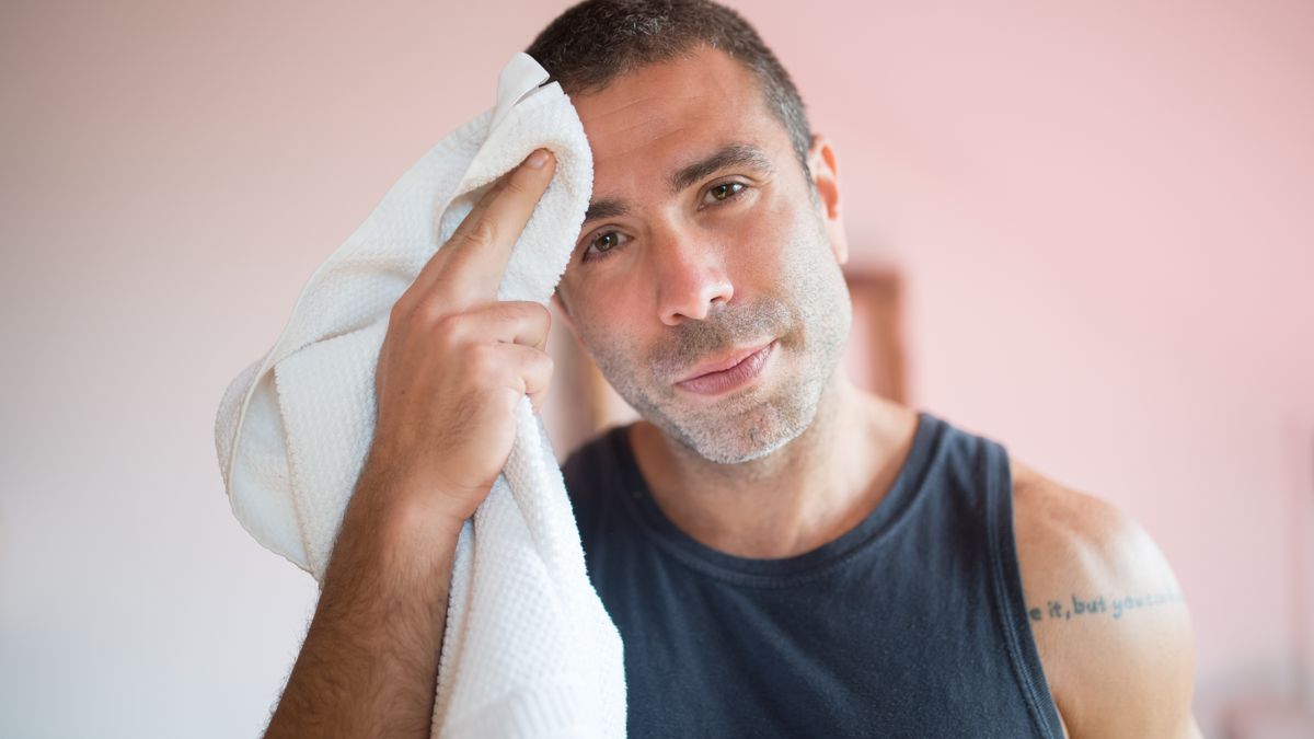 Man wiping sweat from his forehead with a towel after training, a common worry behind searches for trichologists Sunderland near me