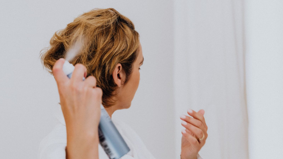 Woman misting a spray product through her hair at home, the kind of daily styling layer behind many trichologists Woking searches