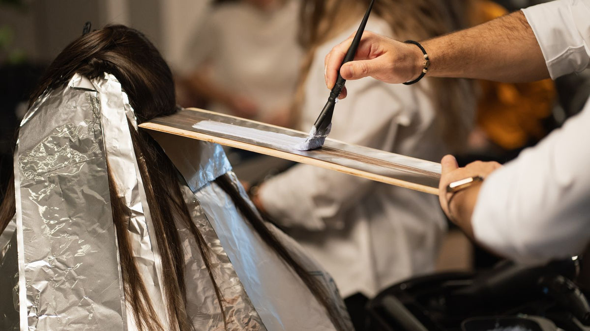 Hairdresser brushing permanent dye onto a client's hair, a common trigger for the itchy scalps trichologists York hear about